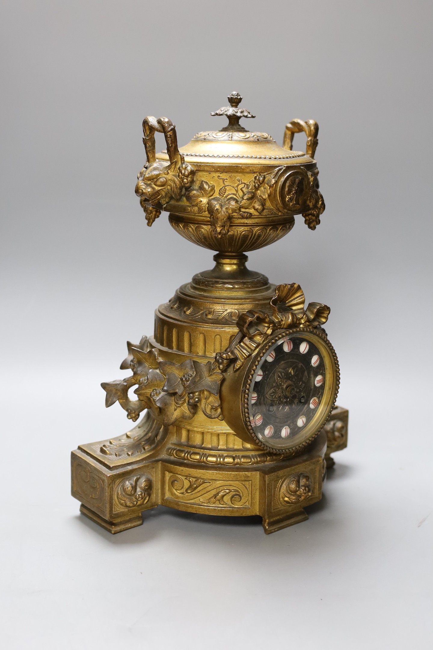 A French gilt metal mantel clock, designed with ornate vines and an urn, 38 cms high